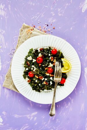 Tasty salad with kale, feta, nuts and tomato on bright background flat layの写真素材