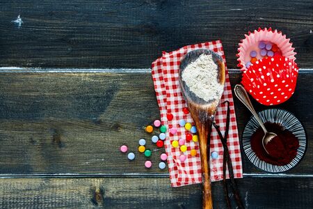 Baking birthday cupcakes ingredients on dark wooden backgroundの写真素材