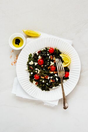 Salad in plate with kale, feta, nuts and tomato flat layの写真素材