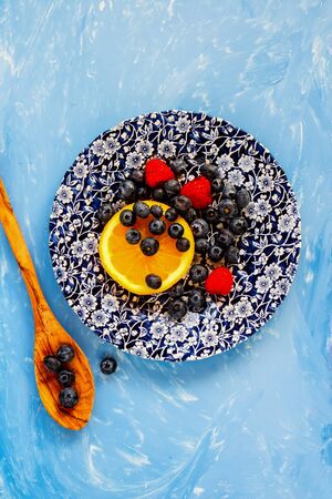 Snack appetizers plate with berries and fruits on blue background, top view, flat layの写真素材
