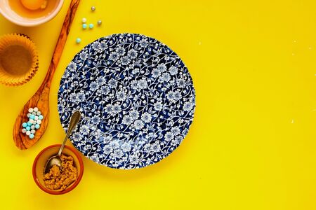 Flat-lay of preparing birthday cupcakes ingredients on yellow backgroundの写真素材
