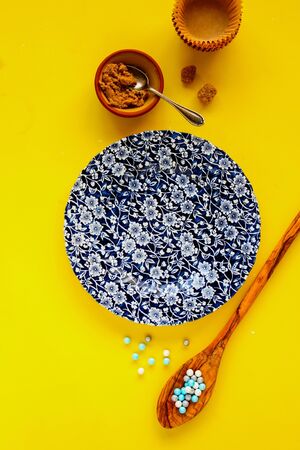 Flat-lay of baking birthday cupcakes ingredients on yellow backgroundの写真素材