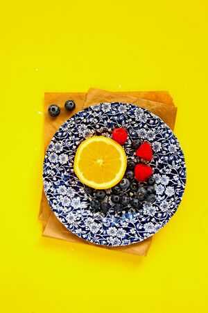 Snack appetizers plate with fruits and berries on yellow background, top view, flat layの写真素材