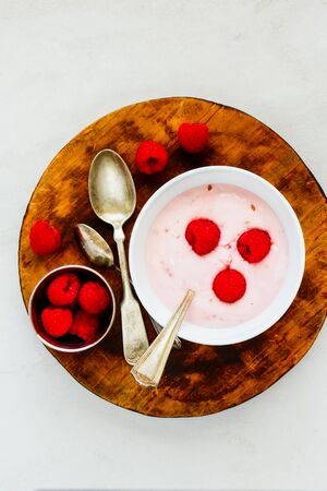 Raspberry yogurt dessert on wooden cutting board with fresh raspberriesの写真素材