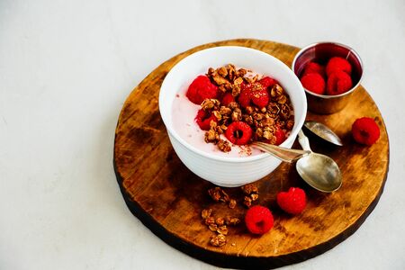 Raspberry yogurt dessert with chocolate granola and fresh berries close-upの写真素材
