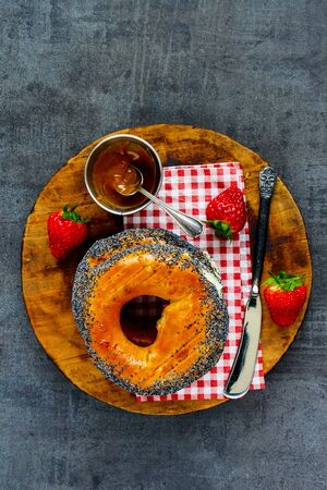 Breakfast set with bagels, fresh strawberries and salted caramel spread on dark surface.の写真素材