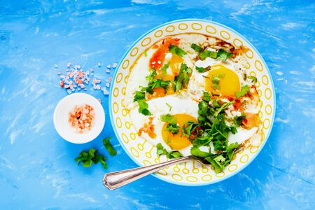 Breakfast plate with fried eggs and salmon on blue background close-upの写真素材