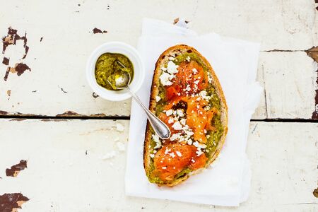 Smoked salmon toast with pesto and feta over old wooden table flat layの写真素材