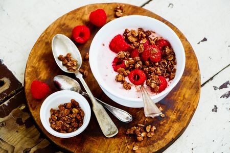 Close-up of yogurt dessert with chocolate granola and fresh berries on wooden tableの写真素材