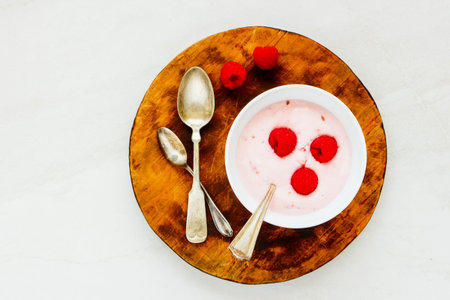 Raspberry yogurt dessert with fresh raspberries on wooden cutting board