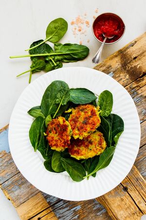 Vegetable pancakes and fresh spinach on plate flat layの写真素材