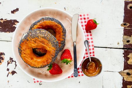Breakfast bagels, salted caramel spread and strawberries on plate flat layの写真素材
