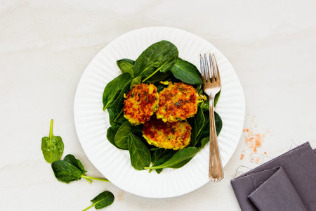 Fresh spinach with healthy vegetable pancakes on plate close-up