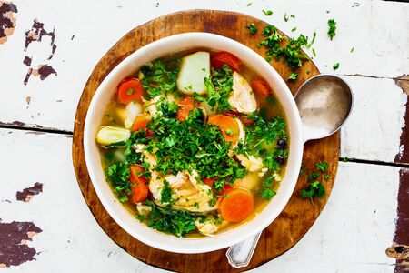 Fish soup with salmon and fresh herbs over old wooden tableの写真素材