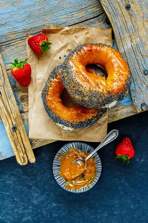 Fresh bagels, salted caramel spread and strawberries top viewの写真素材
