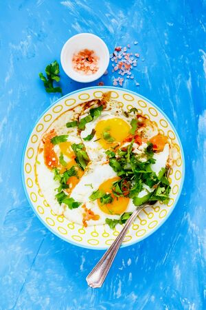 Breakfast with fried eggs and salmon on blue background flat layの写真素材