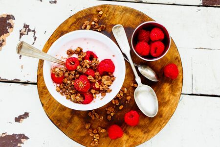Raspberry yogurt dessert with chocolate granola and fresh berries on wooden tableの写真素材