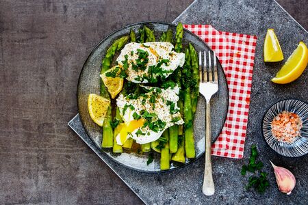 Green aspargus and poached eggs on vintage board close upの写真素材
