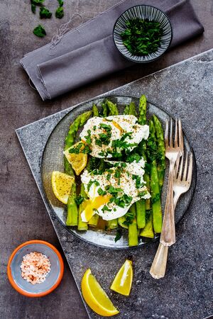 Green aspargus and poached eggs in plate on vintage boardの写真素材