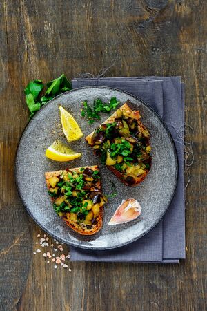 Plate with oven-roasted warm aubergine salad on grilled breadの写真素材