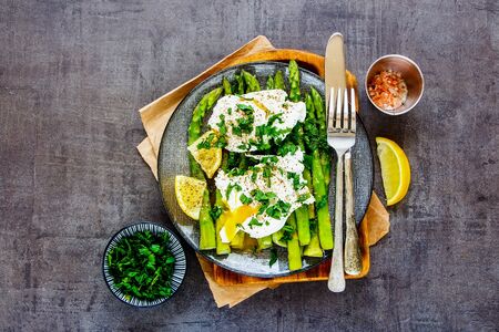 Plate with aspargus and poached eggs on vintage board flat layの写真素材