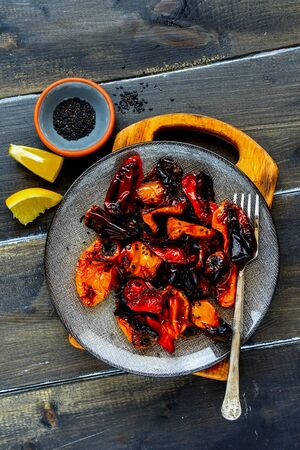 Flat-lay of roasted sweet peppers in plate on dark wooden tableの写真素材