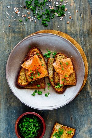 Grilled bread with smoked salmon and fresh herbs in plate flat layの写真素材