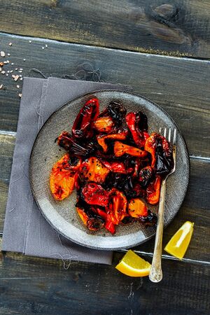 Roasted sweet peppers in plate on dark wooden table flat layの写真素材