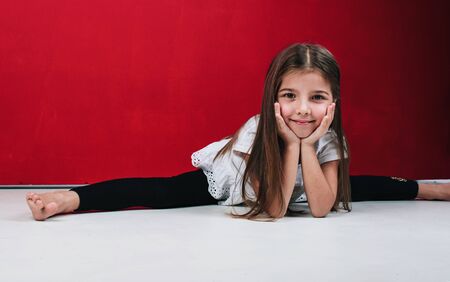 Fashion and beauty. Adorable girl child in casual style. Fashion girl on red background. Little kid with stylish long hair. Happy small child. Fashion look of small model. Little fashionista.の写真素材