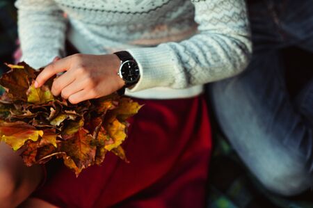 Man and woman with romantic faces on autumn trees background. Relationship and fall time concept. Girl and bearded guy or lovers on date hug. Couple in love with scarves sits on fallen leaves in parkの写真素材