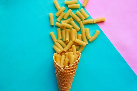 Raw noodles in ice cream cone on blue and pink background. Minimal concept. Italian traditional food conceptの写真素材