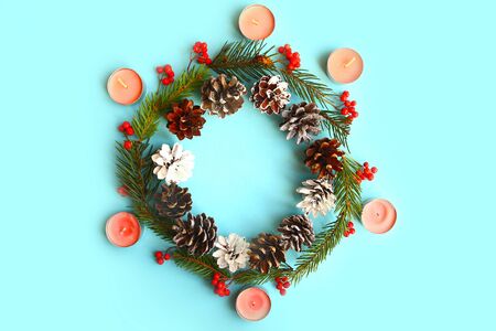 Christmas wreath with fir branches, cones and candles. Blue background. Beautiful Xmas greeting card. Flat lay, top view, copy spaceの写真素材