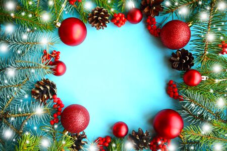 Christmas composition. Frame of fir branches and red Christmas baubles on blue background. Beautiful Xmas greeting card. Copy space for the text. Flat layの写真素材