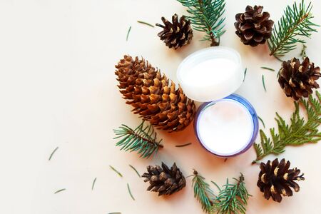Cream container, fir branches and cones on white background, top view. Natural cosmetics conceptの写真素材