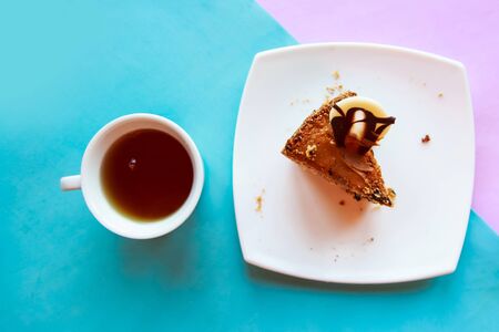 Flat lay photo with tea cup and sliced chocolate cake on blue and pink backgroundの写真素材