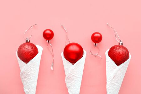 Red Christmas balls in waffle cones on pink background. Flat lay, top view, copy space. Minimal concept. Xmas or New Year greeting cardの写真素材