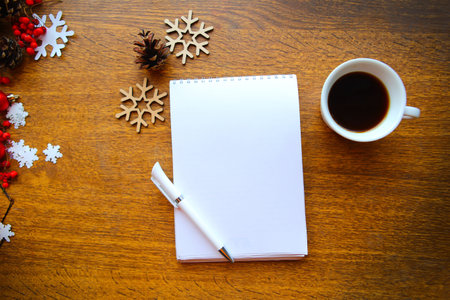 Flat lay photo with Christmas decorations, cup of coffee and open note book on wooden table. New Year begining conceptの写真素材
