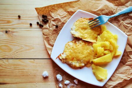 fried potatoes and meat in cheese on a wooden backgroundの写真素材