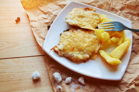 fried potatoes and meat in cheese on a wooden backgroundの写真素材