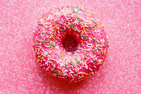 Strawberry donut with colorful sprinkles on pink glitter backgroundの写真素材
