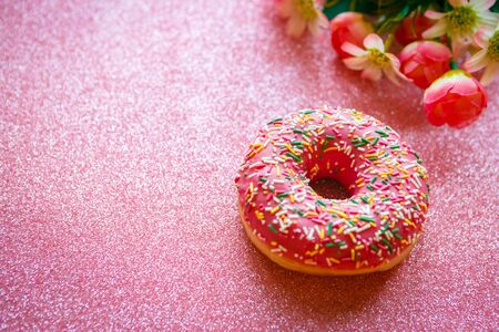 Strawberry donut with colorful sprinkles on pink glitter backgroundの写真素材