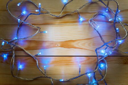 Christmas lights on wooden background, copy space for the textの写真素材