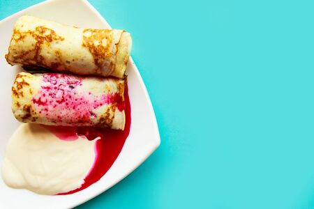 tasty homemade pancakes with sour cream and jam on blue background, flat lay, top view, copy spaceの写真素材