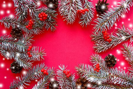 Frame of  spruce branches and decorations on red background. Flat lay, top view, copy spaceの写真素材