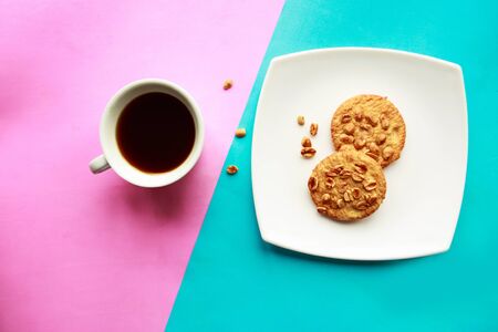 Homemade cookies with nuts and coffee cup on geometric blue and pink backgroundの写真素材