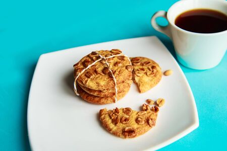 Tasty cookies with nuts on white plate and cup of coffeeの写真素材