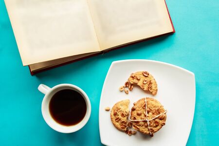 Flat lay photo with coffee cup, open book and cookies on blue background. Flat lay, top viewの写真素材
