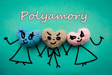 Three knitted hearts on blue background and the text - polyamoryの写真素材