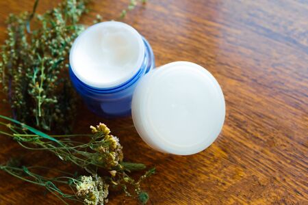 cream container and herbs on wooden tableの写真素材