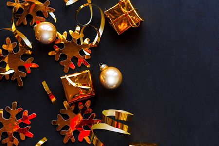 Golden decorations on black background. Flat lay, top view, copy space. Merry Christmas and Happy New Yearの写真素材